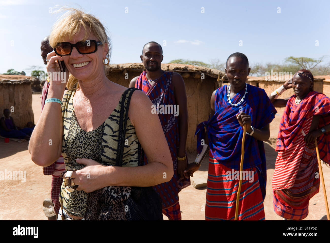 Female tourist phoning with a mobile phone in a Massai Village Coast Kenya Stock Photo