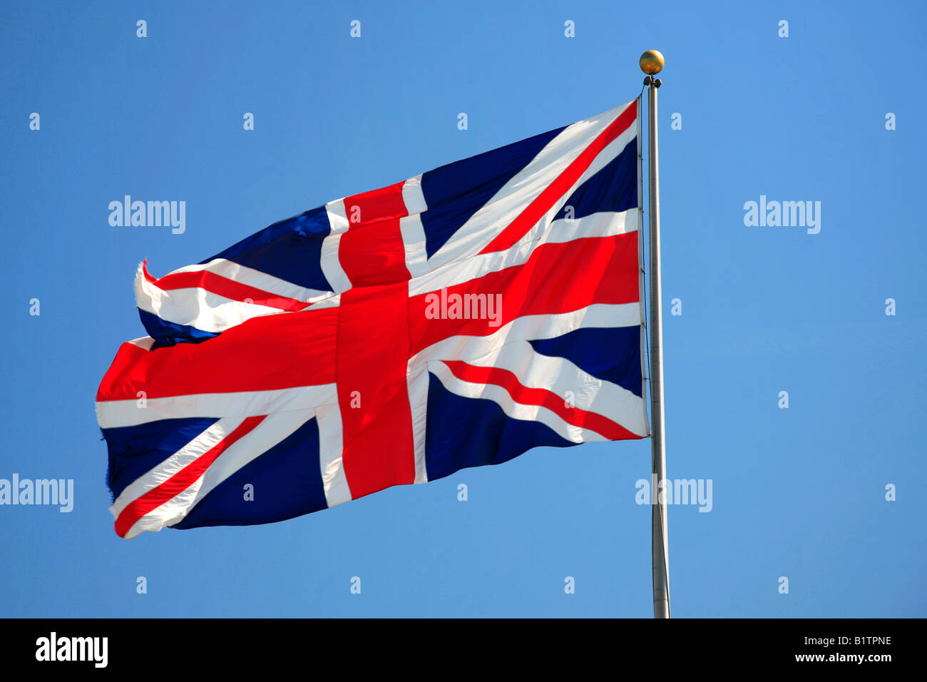 Union jack flag fluttering in the wind against a blue sky England ...