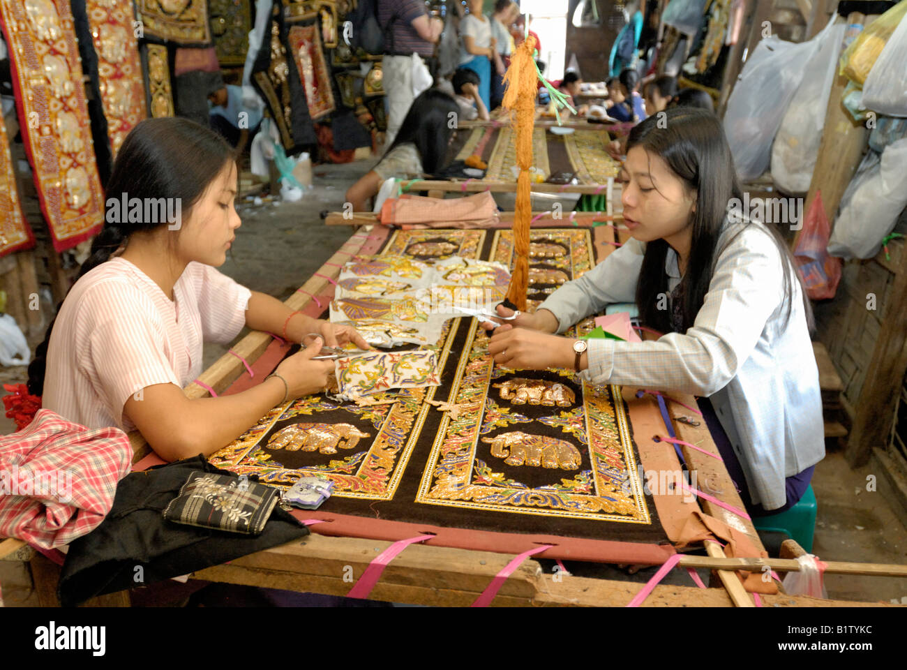 women stitching tapestries in a workshop of tapestry marionettes and other souvenirs, MANDALAY AMARAPURA, MYANMAR BURMA BIRMA Stock Photo