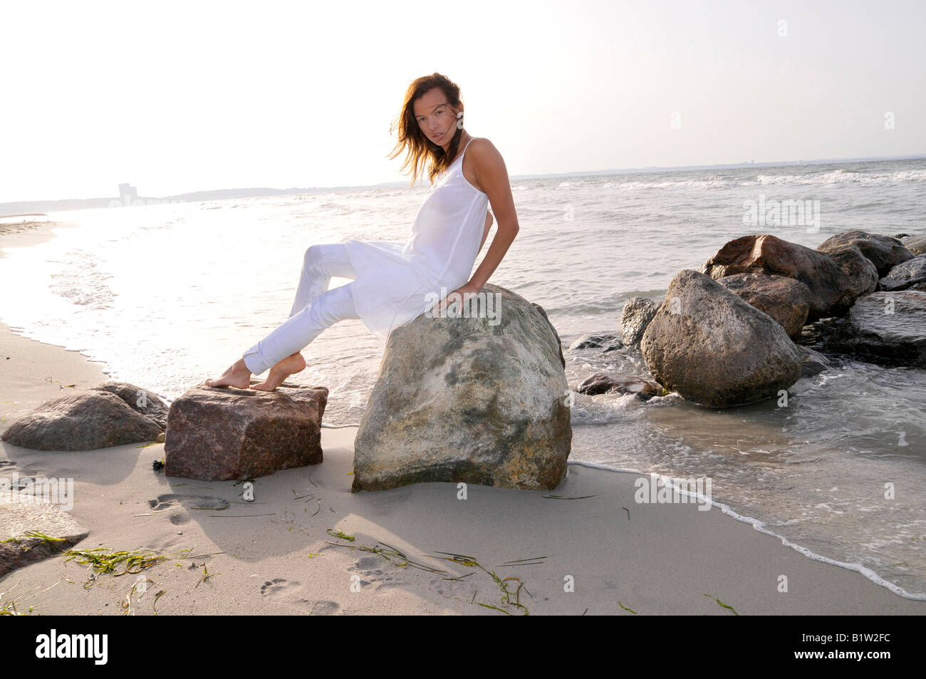 young woman 24 sitting and relaxing at beach, backlight, free, easy, happy, holidays, vitality, chillout, backlight, brunette Stock Photo
