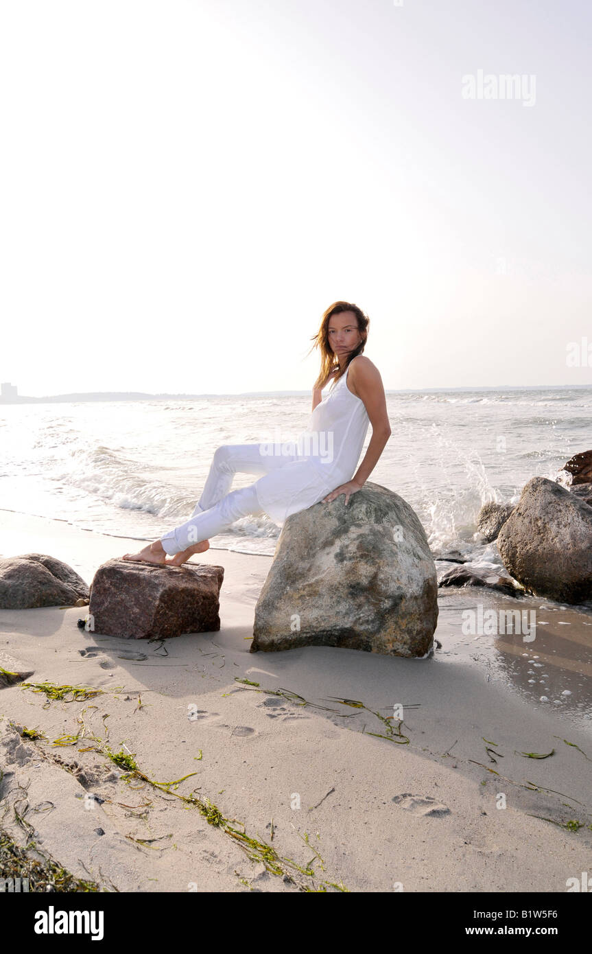 young woman 24 sitting and relaxing at beach, backlight, free, easy, happy, holidays, vitality, chillout, backlight, brunette Stock Photo