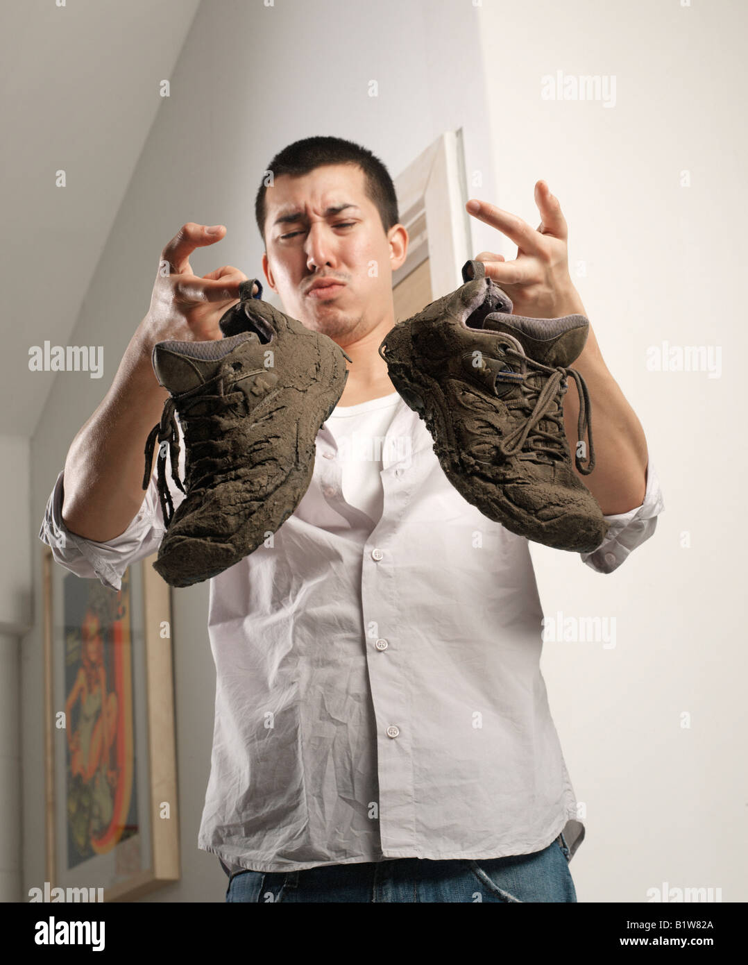 oriental man holding smelly and dirty shoes Stock Photo