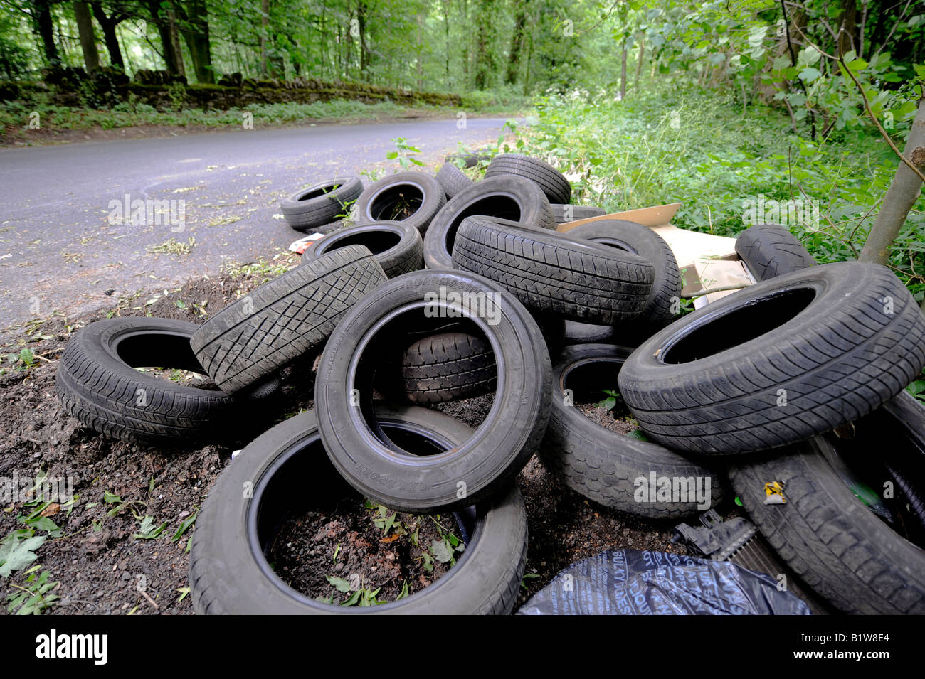 Illegally dumped Tyres left by fly-tippers at the side of a country lane in the Cotswolds. Picture by Jim Holden. Stock Photo