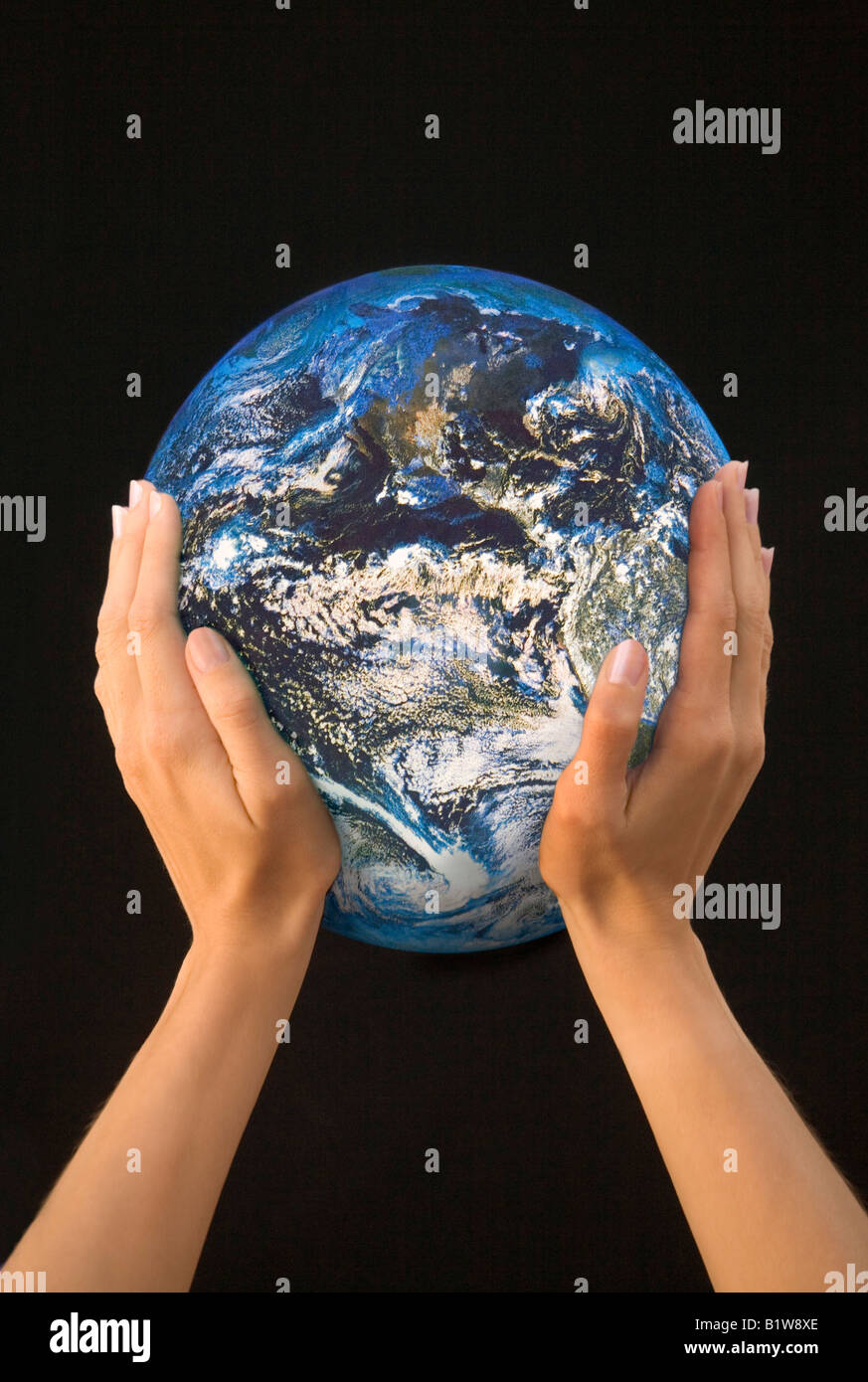 Hands against a black background, holding the earth in a gesture of protection. Stock Photo