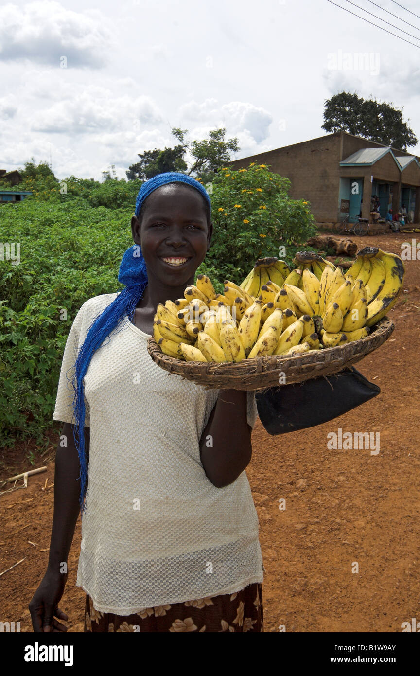 Smiling African woman holding basket of ripe bananas to sell Kenya Africa Stock Photo
