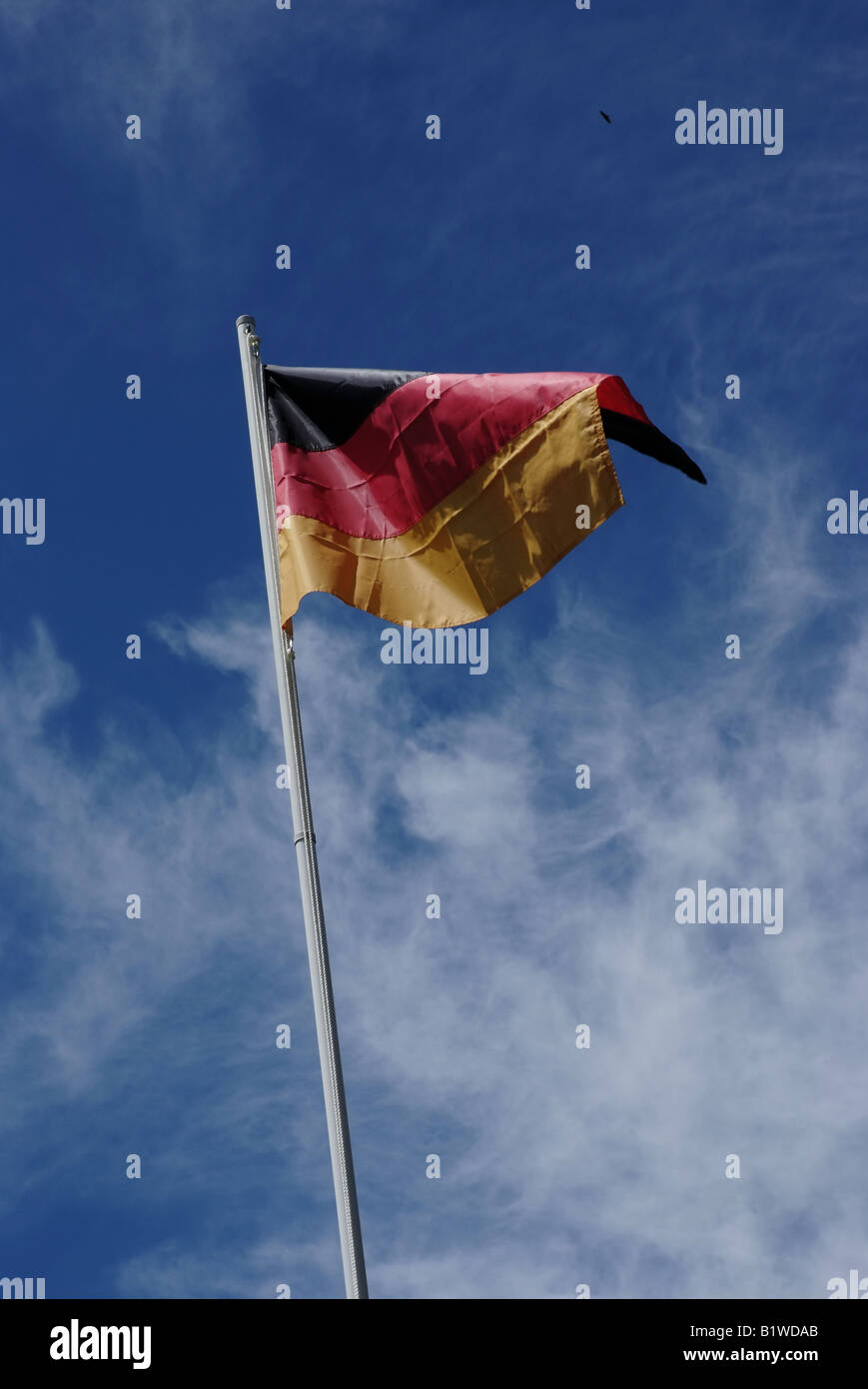 German Flag in front of blue sky with light clouds Stock Photo