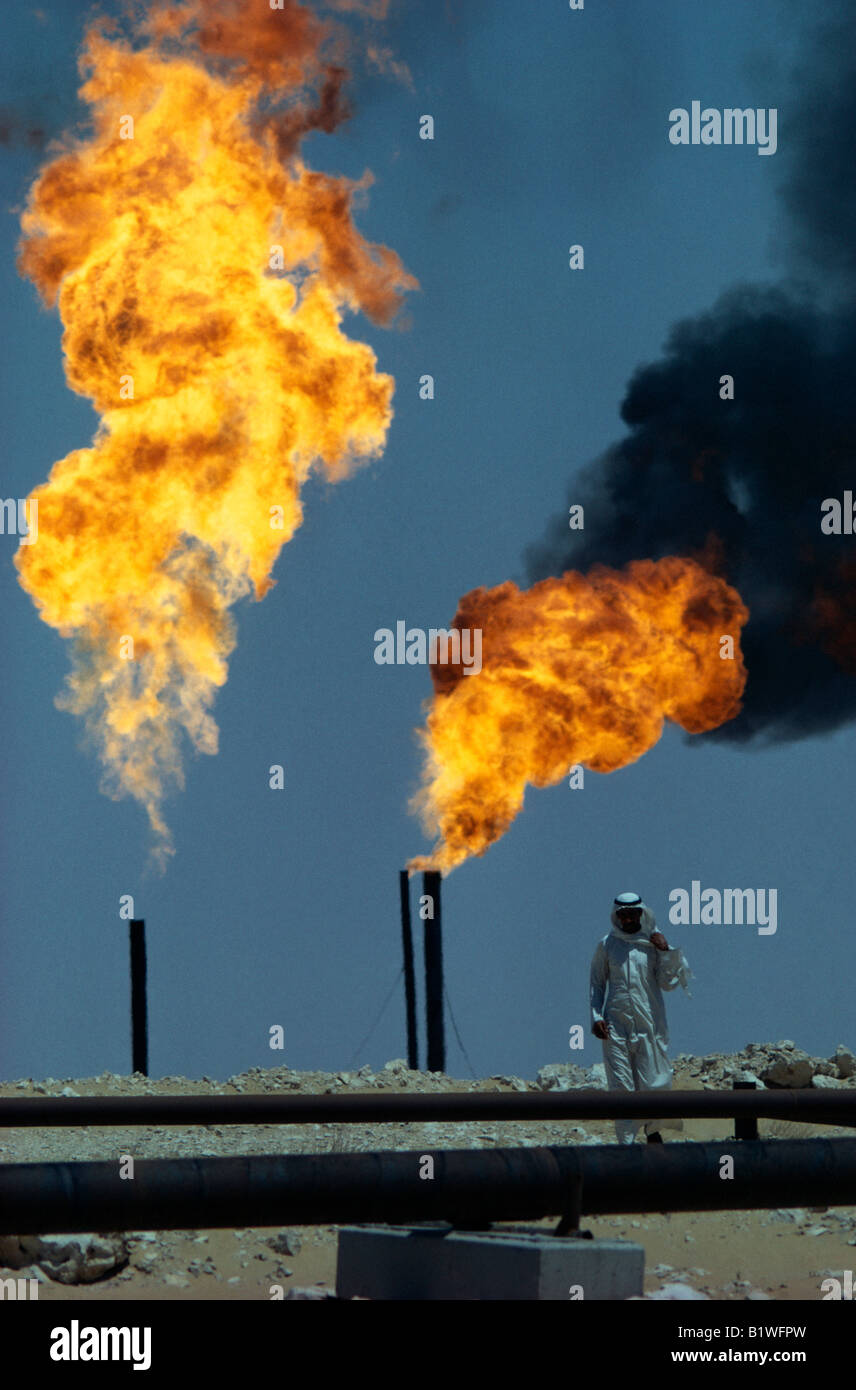 SAUDI ARABIA Middle East Gulf State Flaming gas burn off on oil field with man walking towards pipes Stock Photo