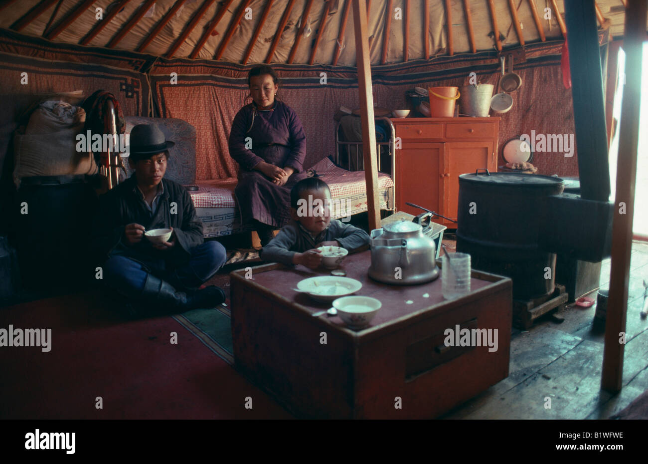 MONGOLIA Asia People Nomad Family Interior of yurt with family having ...