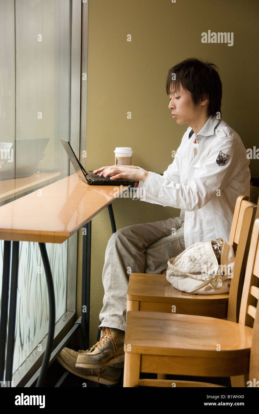 Kyoto, Japan. A young man working on a laptop computer using the free wifi  in a branch of Starbucks coffee shop Stock Photo - Alamy