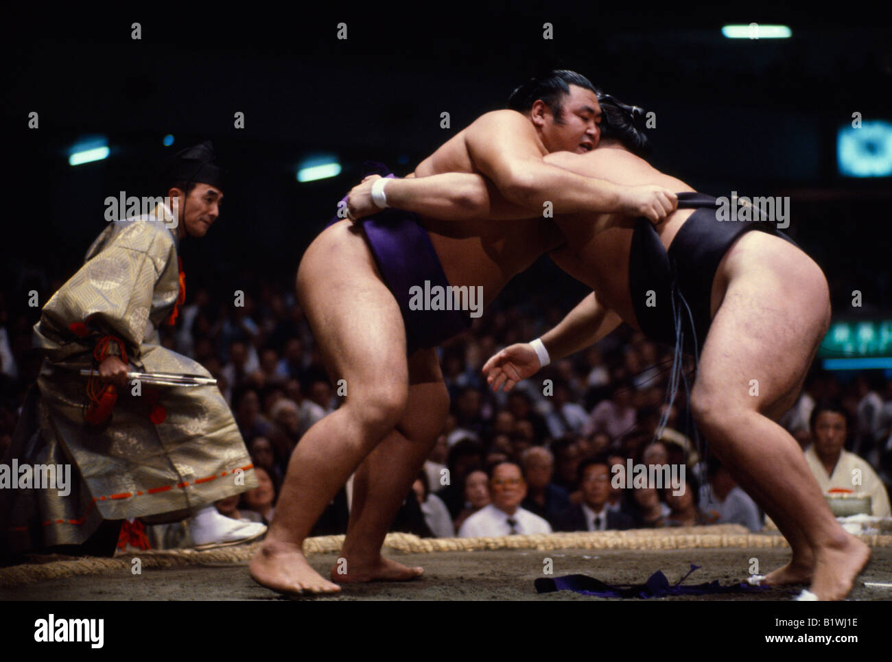 JAPAN Samurai Sumo wrestlers in ring watched by referee wearing the costume of a shogun. Sumo is an ancient form of wrestling Stock Photo