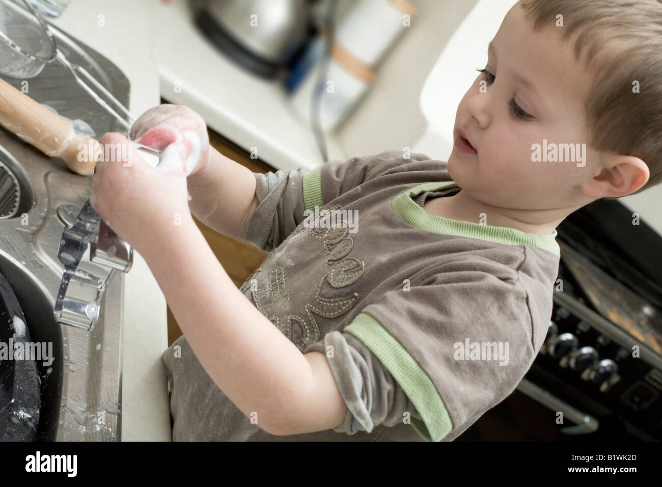 Child Washing Up at Kitchen Sink Stock Photo