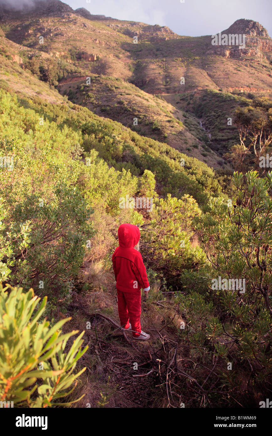 Young child in red jump suit on a Table Mountain path gazing at a distant waterfall Fybos all around Stock Photo
