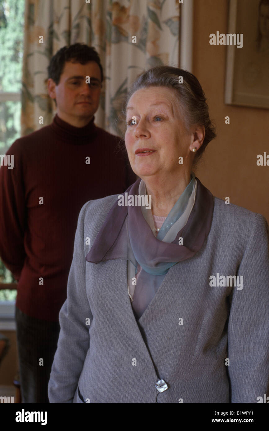 younger man standing behind older woman looking concerned Stock Photo