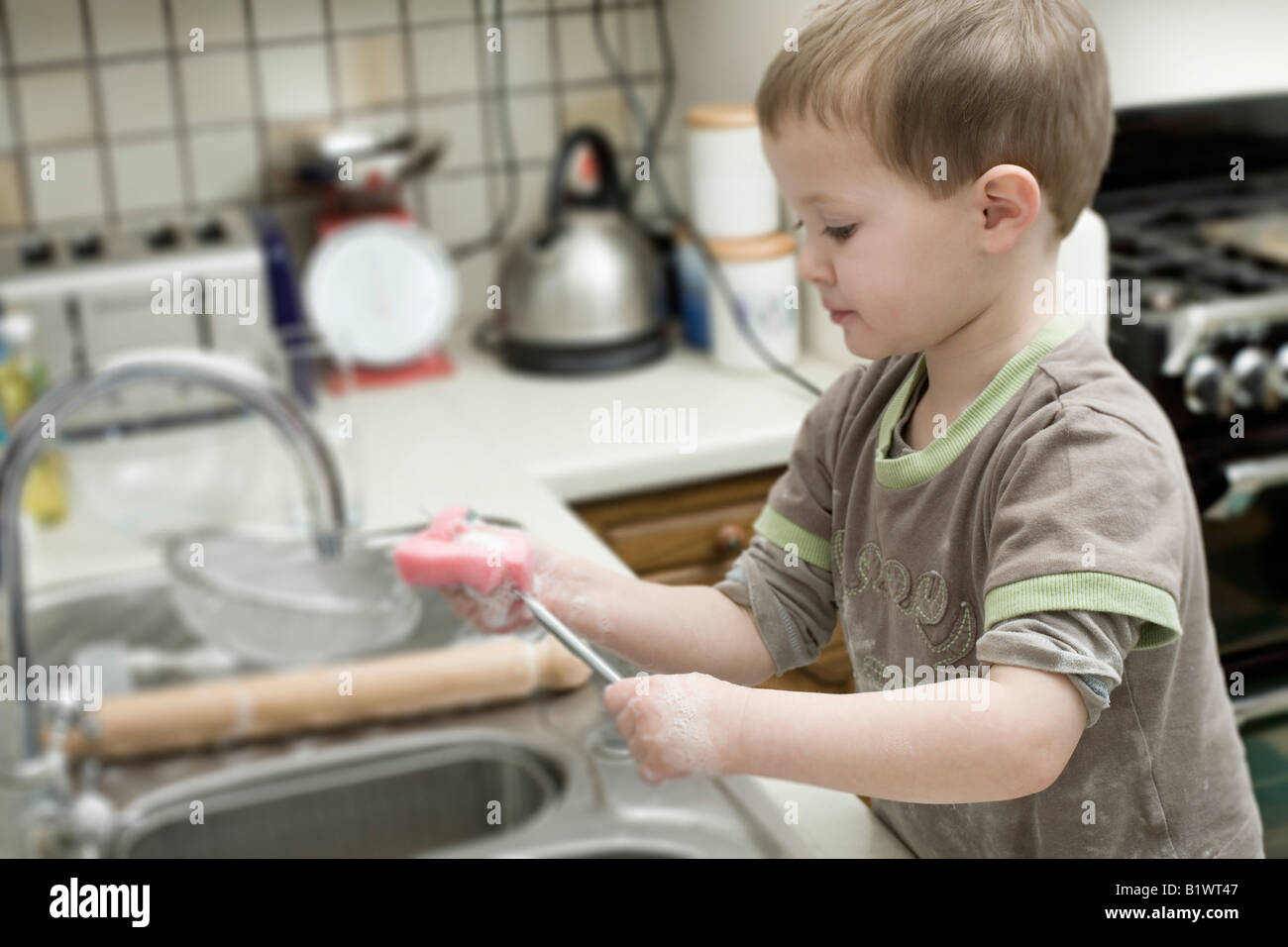 Child Washing Up at Kitchen Sink Stock Photo