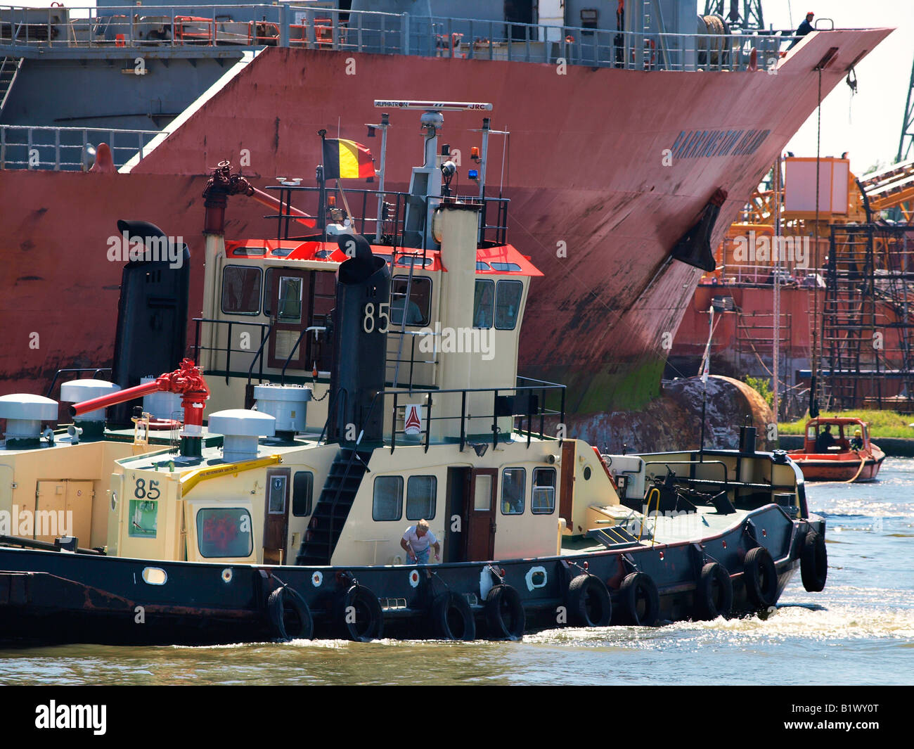 Tugboat pushing and nudging a bigger ship into a drydock for repairs Antwerp port Flanders Belgium Stock Photo