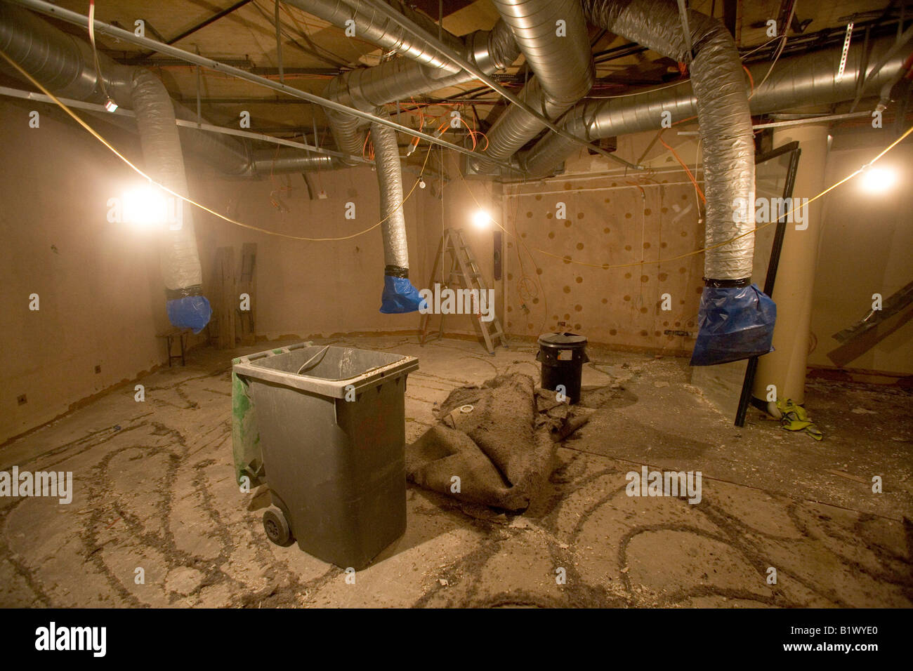 A bundle of rolled up carpet sits in the middle of a room. Stock Photo