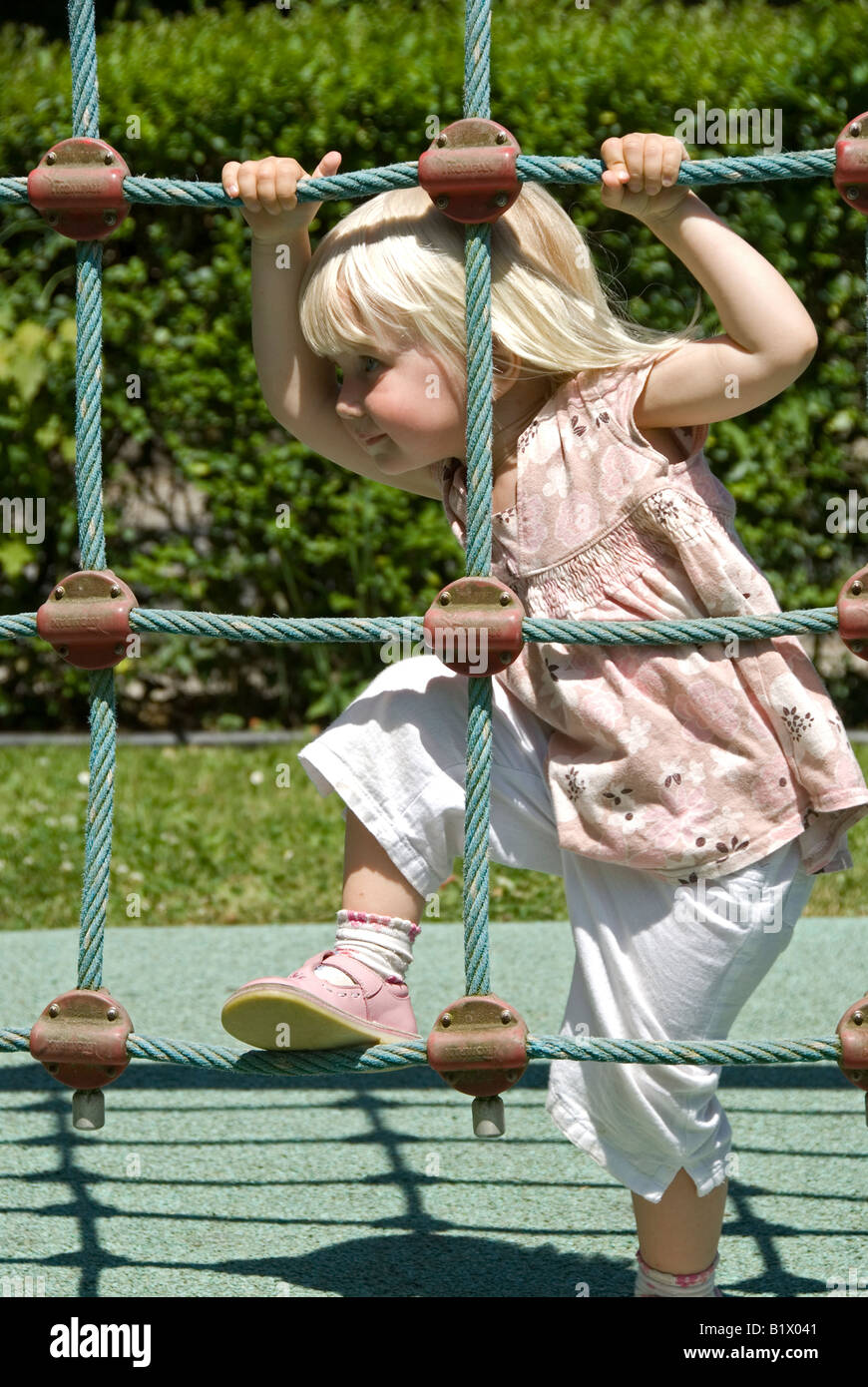 Stock photo of a two year old child climbing a rope climbing frame