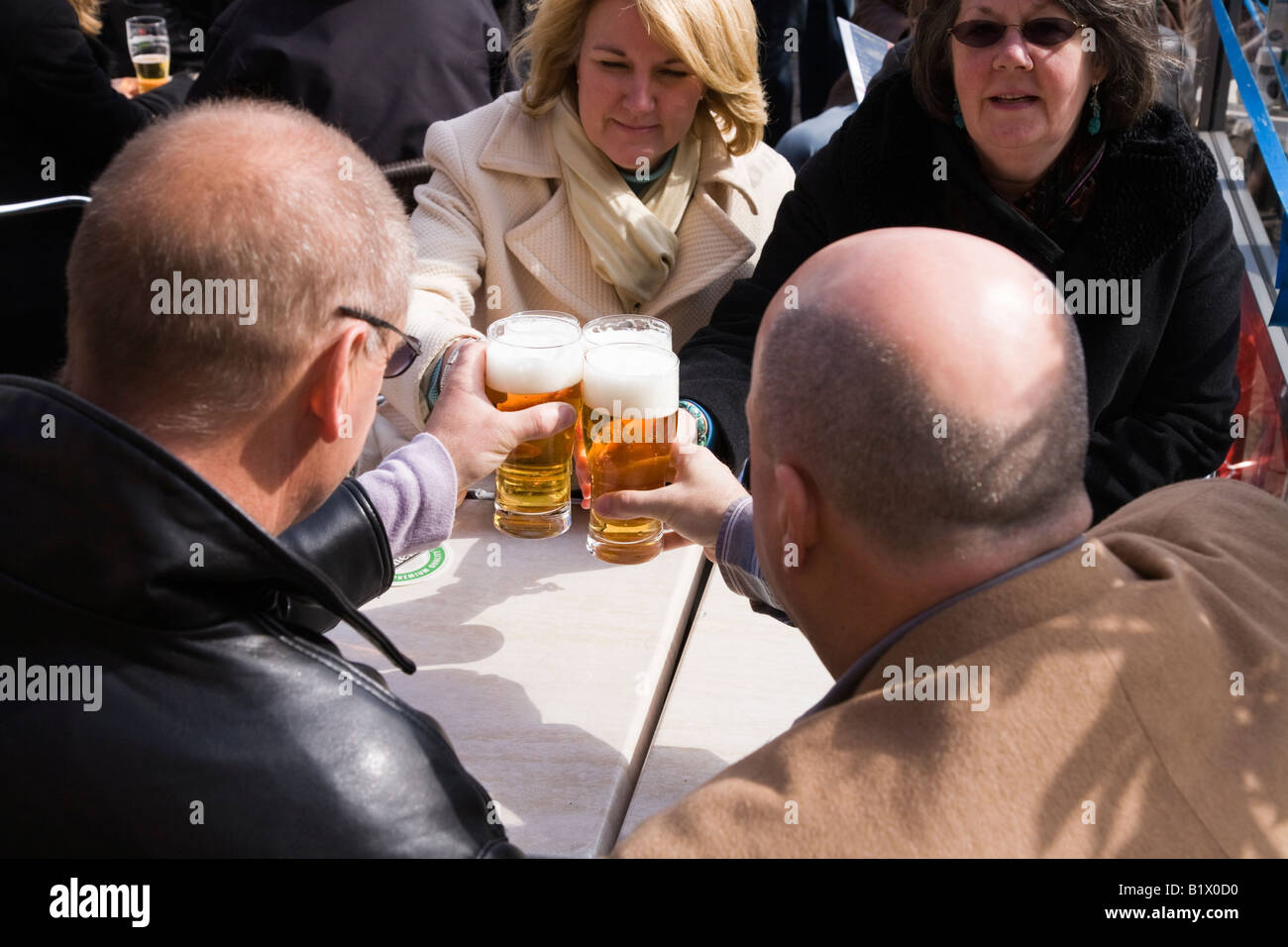 Two couples toast with a beer at street restaurant table in Markt Square, in Delft. Netherlands. Stock Photo