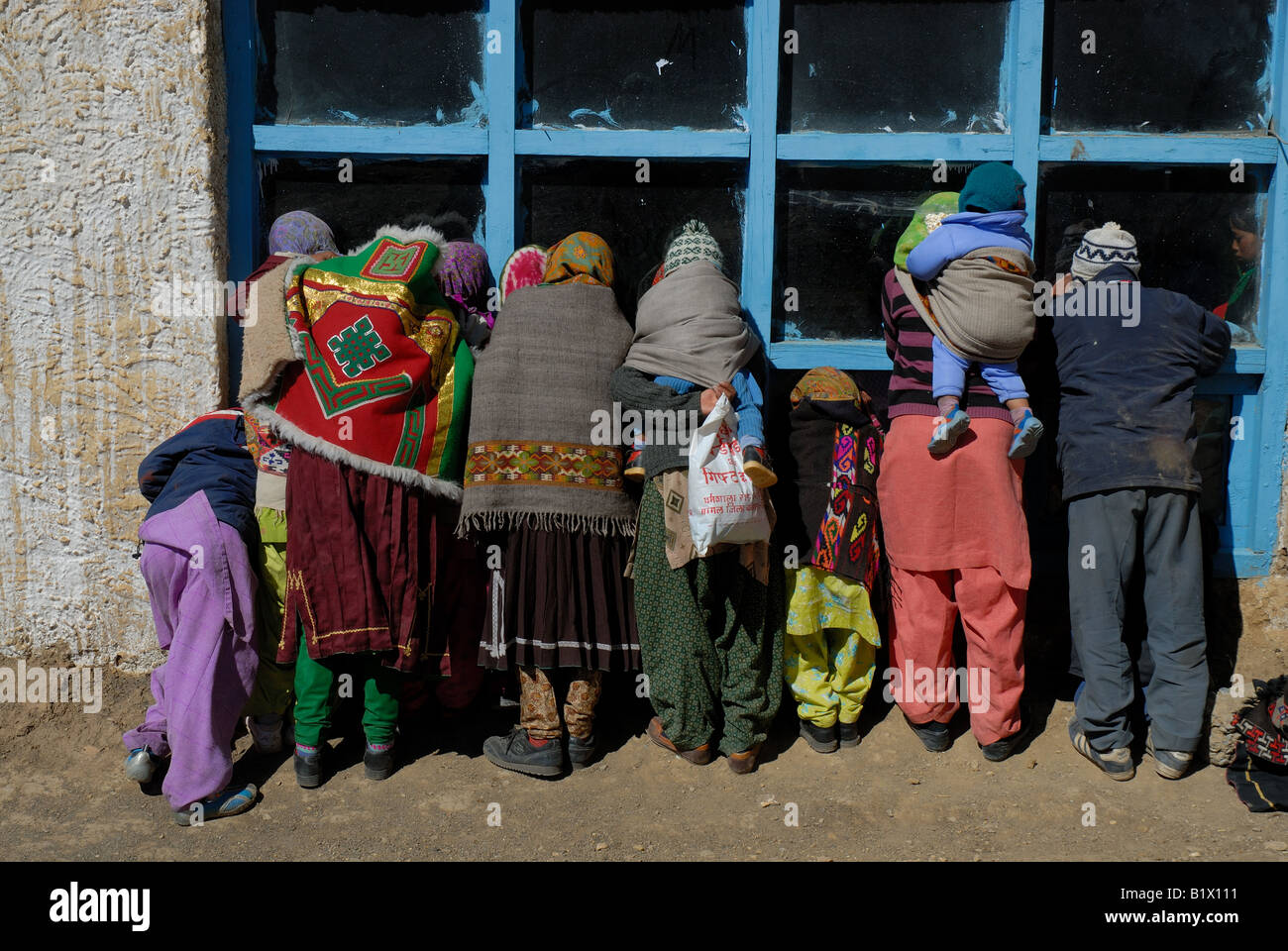 Villagers curiously peep at a dance rehearsal to honor the crowning of head lama of the Komik monastery. Spiti valley, Himachal Stock Photo