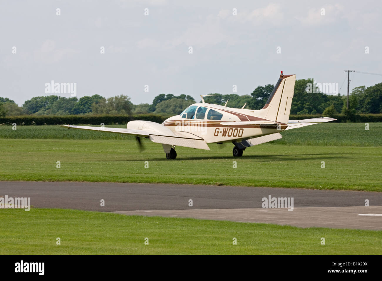 Beech 95-B55A Baron G-WOOD taxiing along runway with flaps down after landing at Breighton Airfield Stock Photo