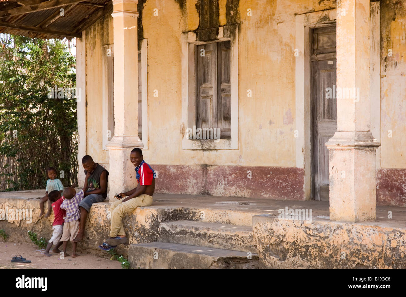 Family sitting in front of a dilapidated colonial villa on Ibo island. Mozambique Stock Photo