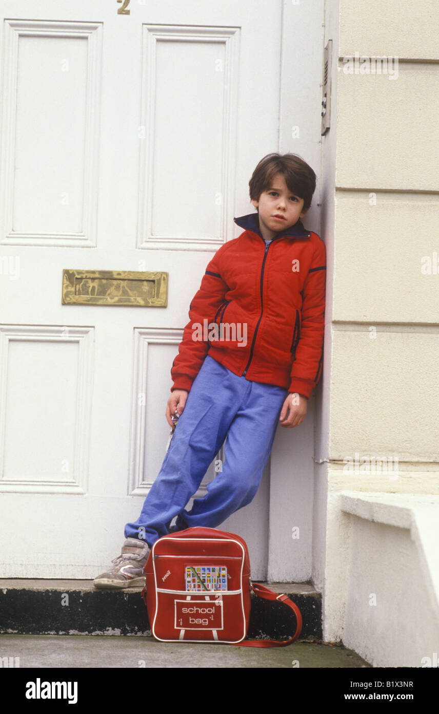 Child sitting on doorstep waiting for parents to come home Stock Photo