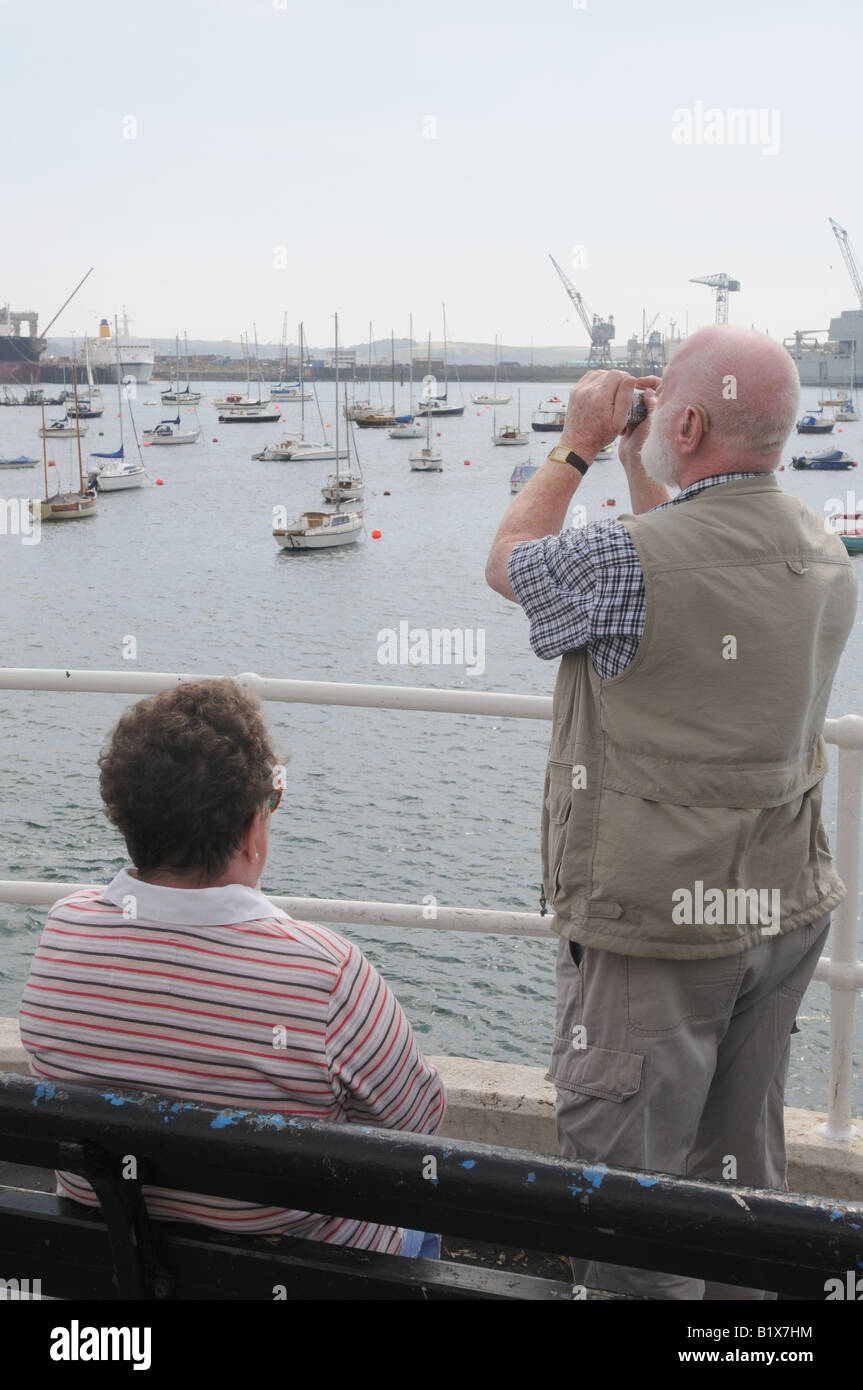 A tourist on falmouth pier looking through binoculars, Stock Photo