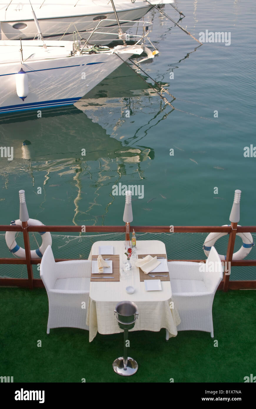 Vertical elevated view of an empty table for two set outside ready for dinner service at an expensive waterside restaurant Stock Photo