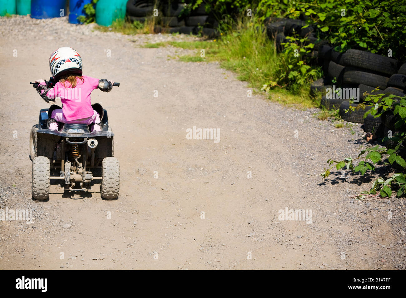 Girl riding quadbike on dirt track Stock Photo