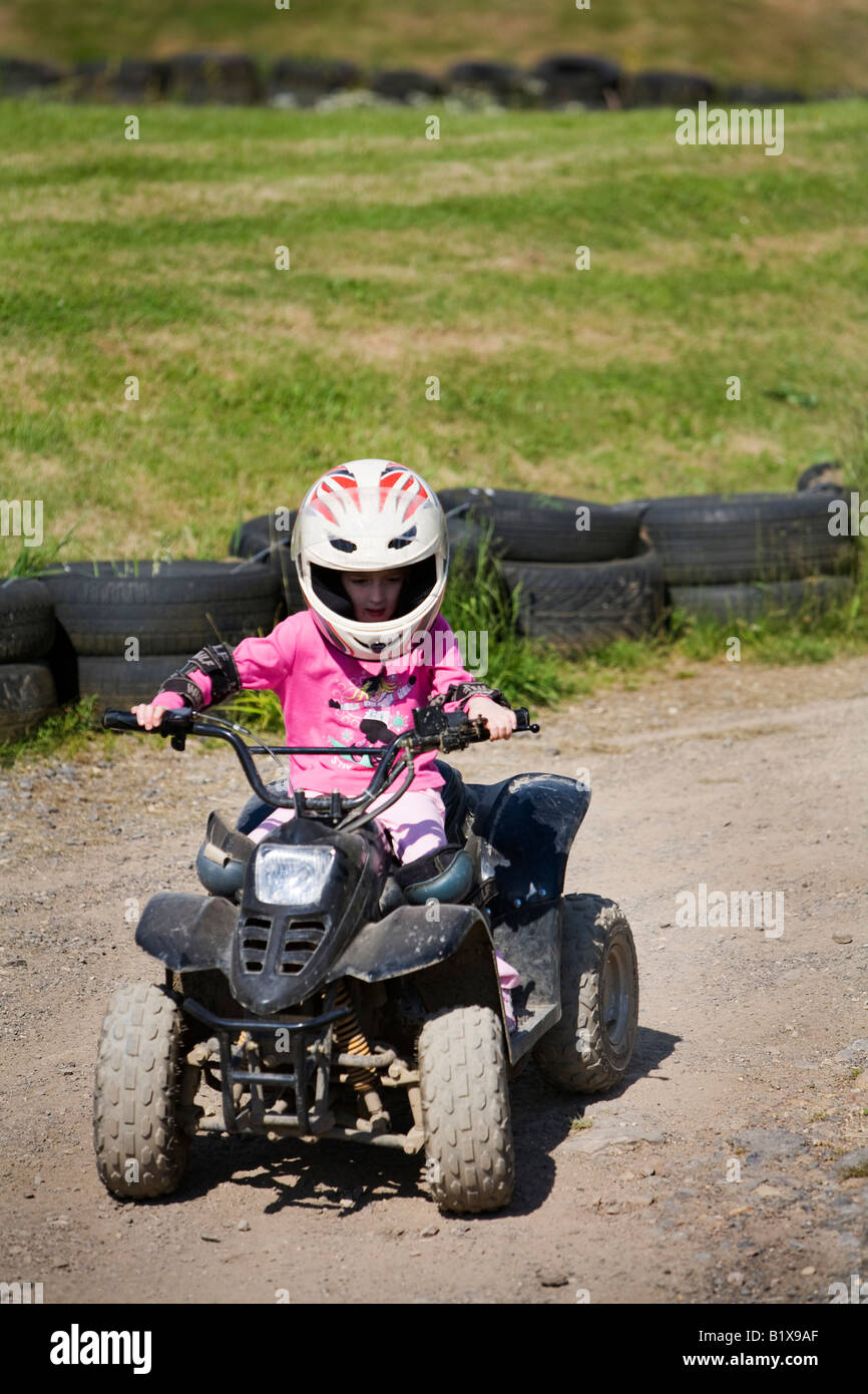 Girl riding quadbike on dirt track Stock Photo