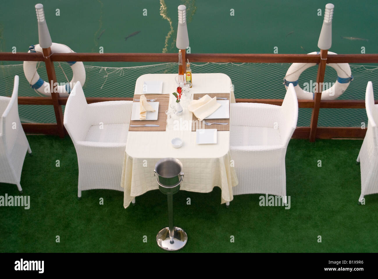 Horizontal elevated view of an empty table for two set outside ready for dinner service at an expensive waterside restaurant Stock Photo