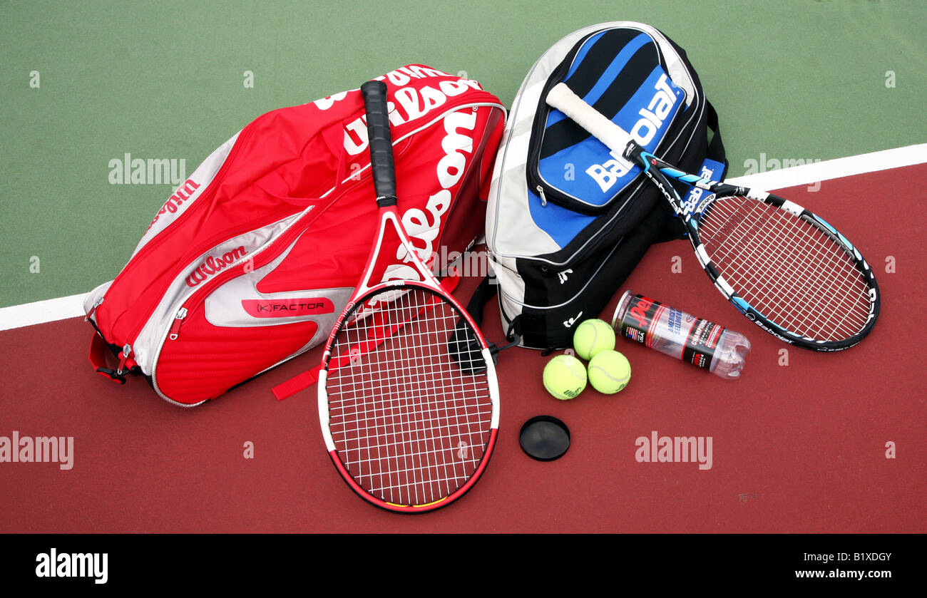 Two tennis racket bags with two tennis rackets laying crossed on top