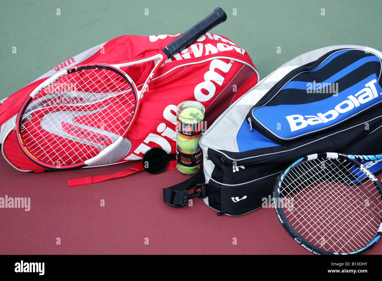 Two tennis racket bags with two tennis rackets laying crossed on top