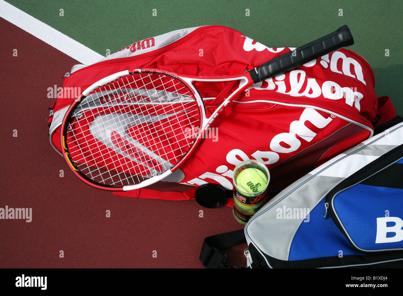 Two tennis racket bags with two tennis rackets laying crossed on top
