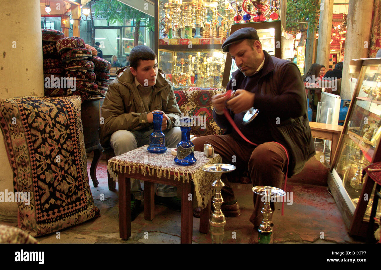 An exprienced professional teaches his junior assistant how to prepare Shisha in a beautiful tea garden in Istanbul. Stock Photo