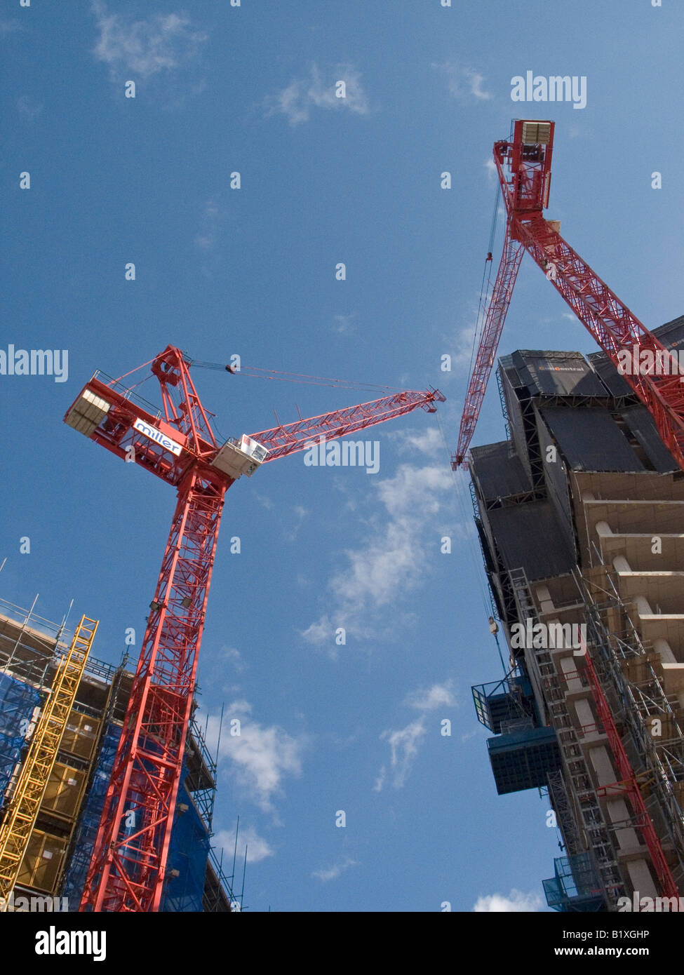 city centre building under construction with red tower cranes blue sky Stock Photo