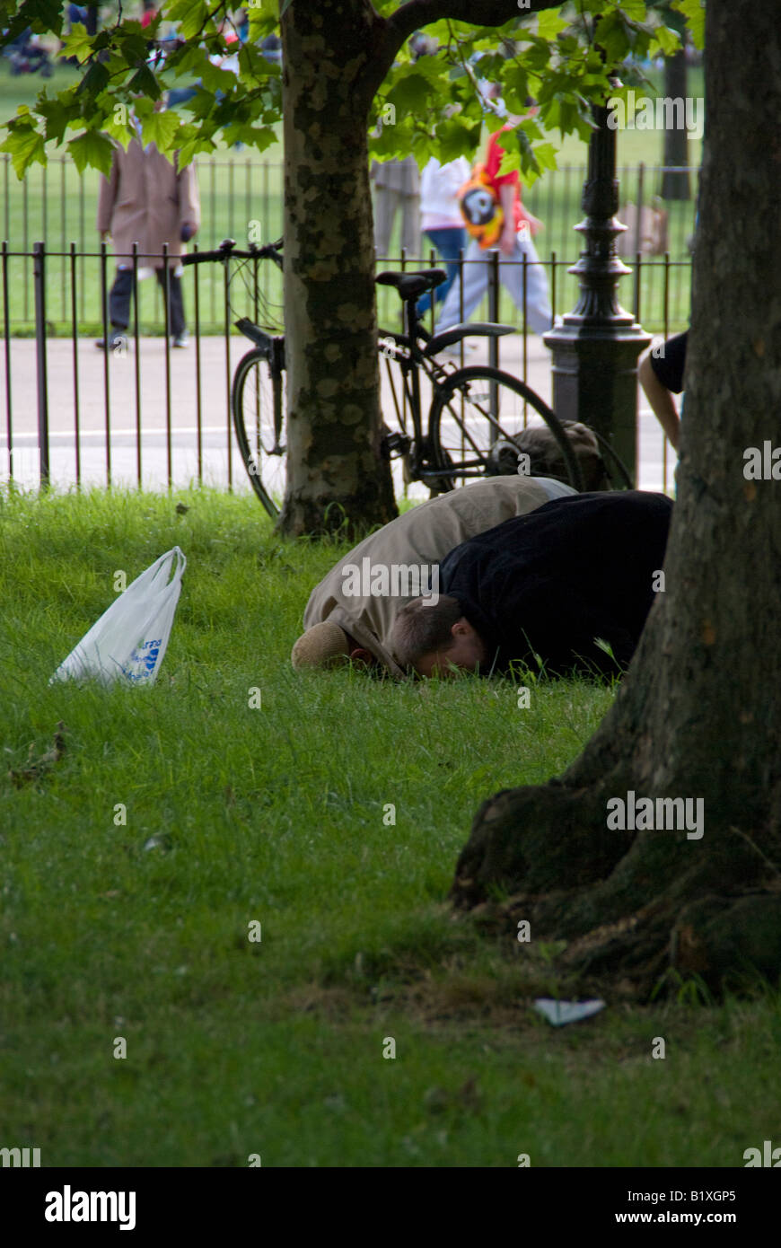 Two muslims bowing towards mecca in hyde park Stock Photo