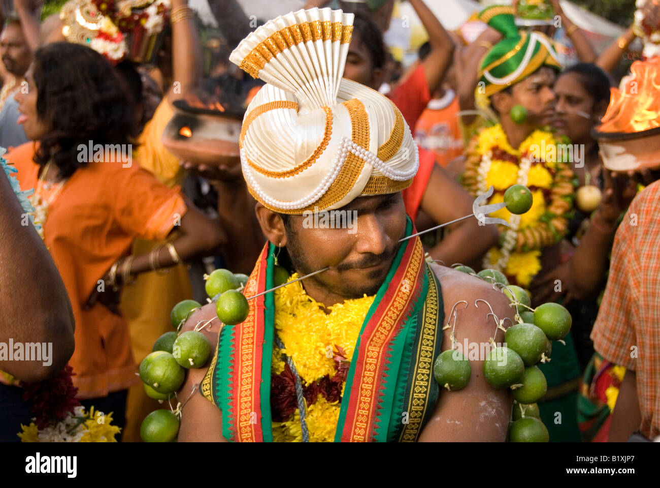 DEVOTEE WITH SKEWER PIERCING THROUGH CHEEK AT THE ANNUAL HINDU FESTIVAL OF THAIPUSAM BATU CAVES KUALA LUMPUR MALAYSIA Stock Photo