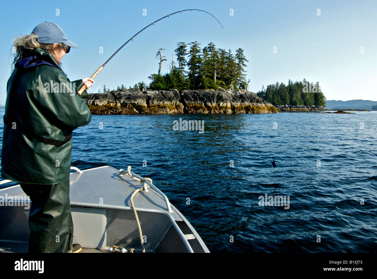 Woman playing a silver coho salmon fish at Gnarled Island in northern British Columbia Stock Photo