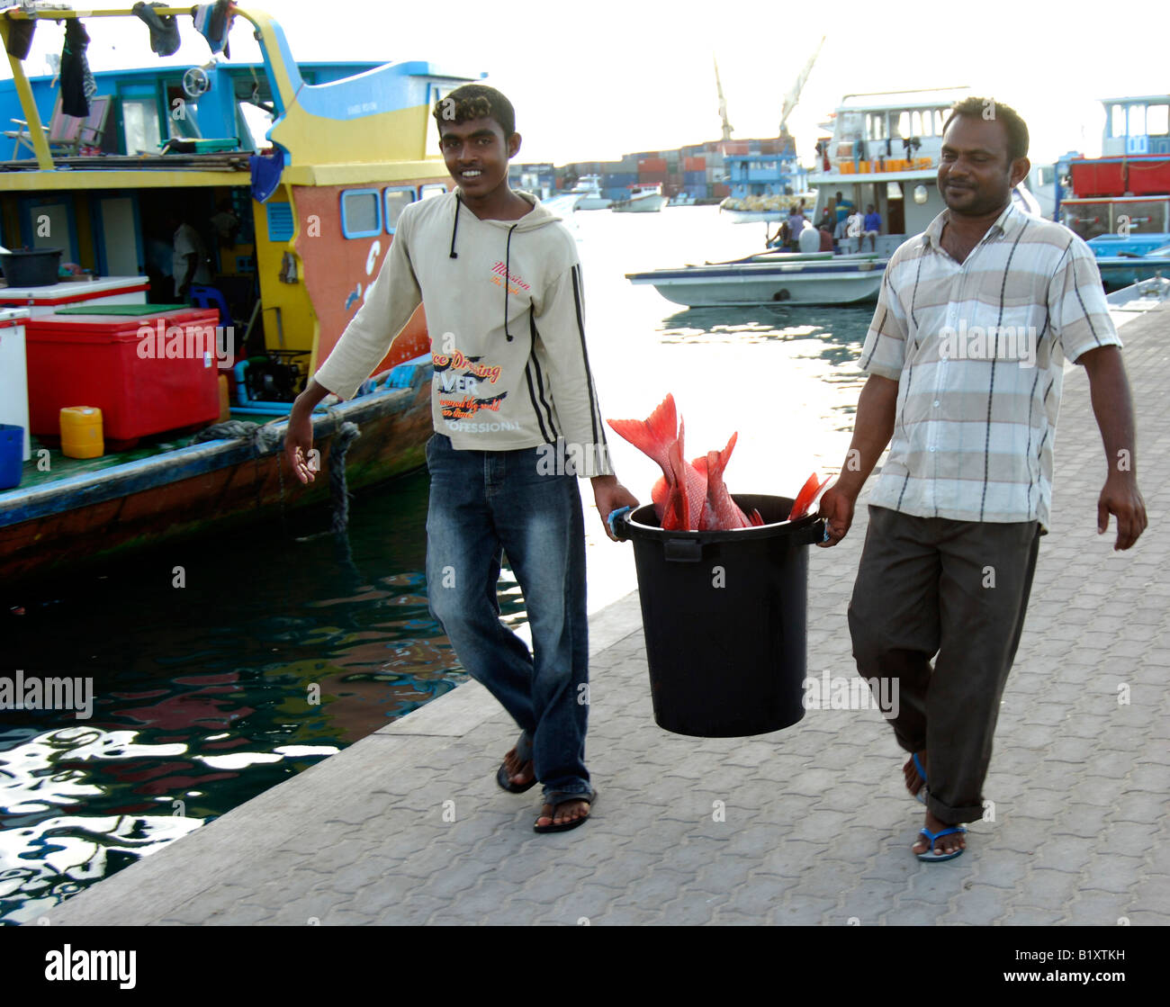 two fishermen carrying fish in a pail Male Maldives Stock Photo