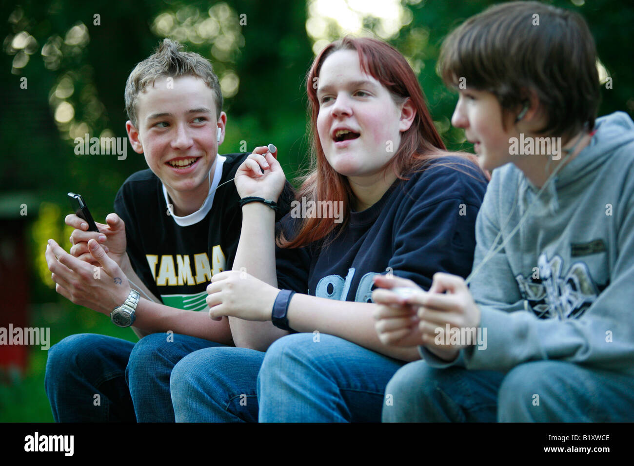 two boys and a girl listening to music together Stock Photo