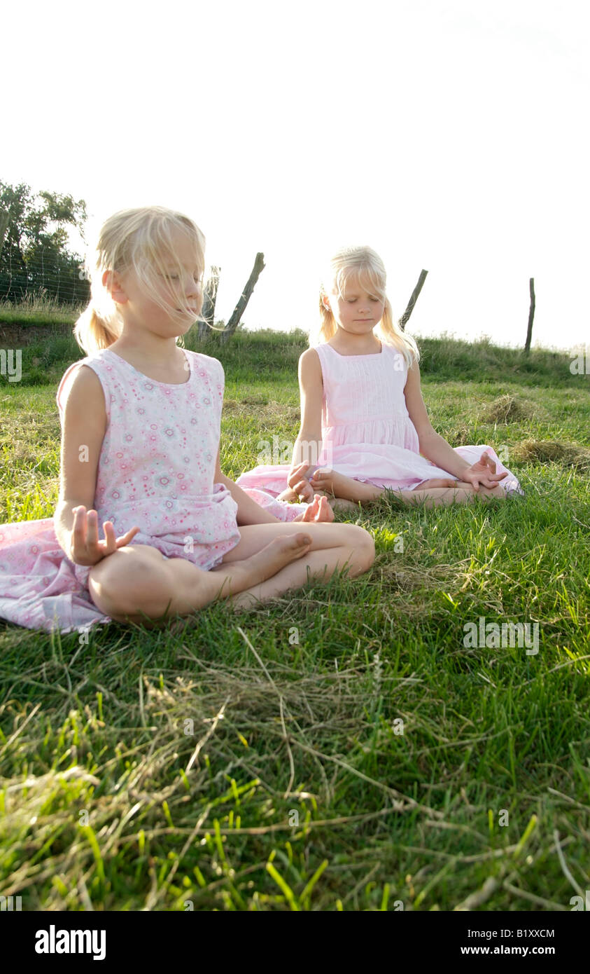 Portrait of two girl friends practicing yoga in summer, outdoor lotus seat Stock Photo