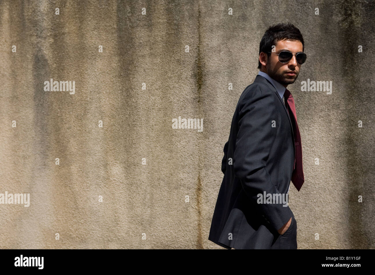 business man wearing suit and sunglasses walking outdoors hands in B1Y1GF