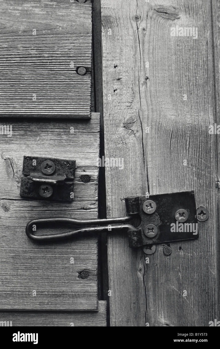 Black and white close up of a worn wooden shed door with a misaligned latch off centre Stock Photo
