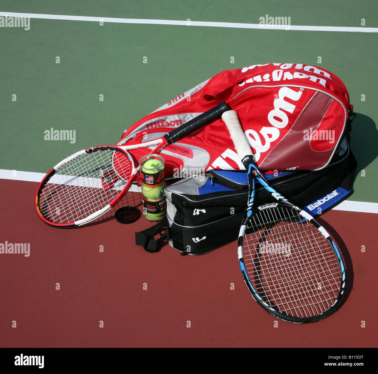 Two tennis racket bags with two tennis rackets laying crossed on top