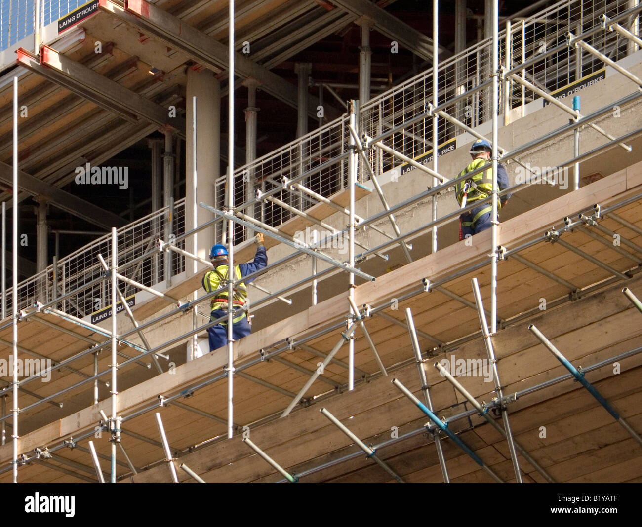 two men erecting scaffold on a building under construction Stock Photo