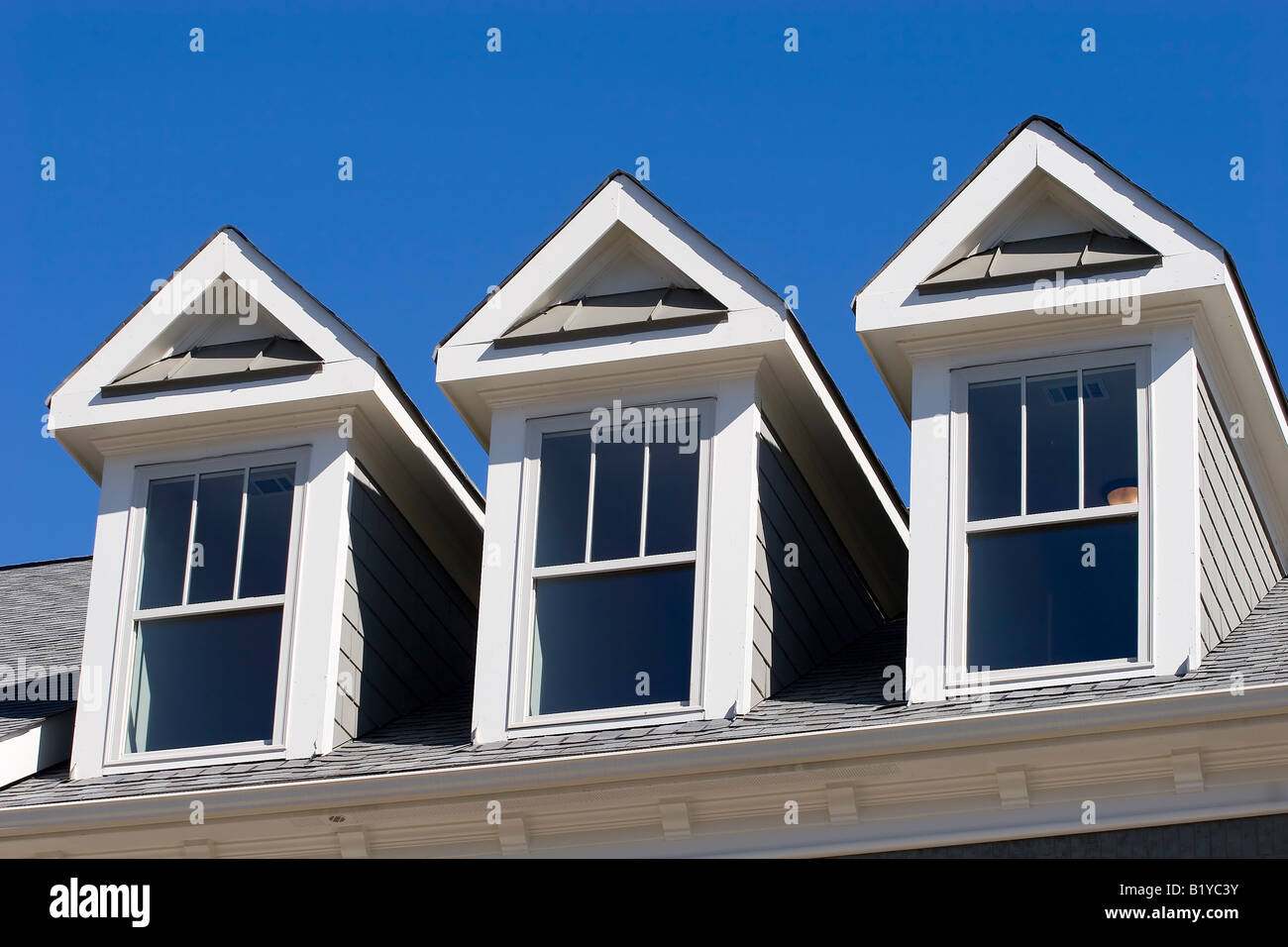 A Roof Line With Three Dormers Against A Blue Sky Stock Photo