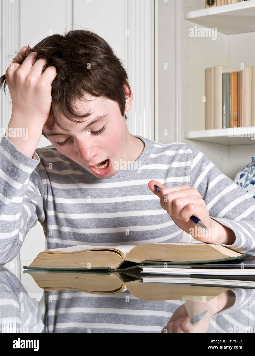 Young teenager boy yawning over a boring book Stock Photo