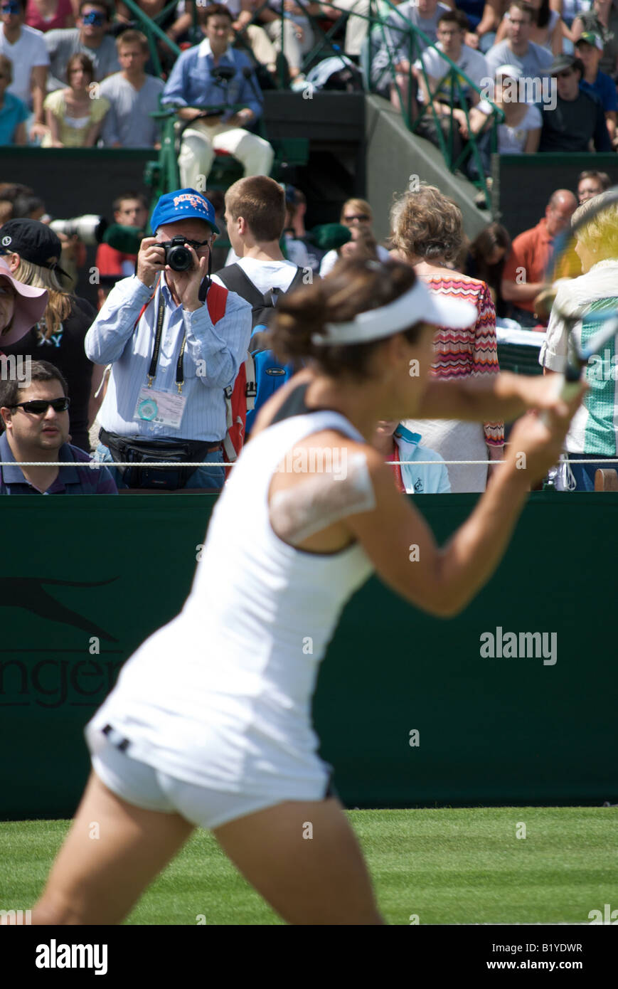 A photographer takes a picture as Nuria Llagostera Vives returns a shot during the opening day of Wimbledon 2008 Stock Photo