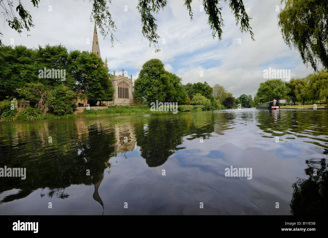 In Stratford-Upon-Avon a narrowboat potters past Holy Trinity Church on the river Avon. Picture by Jim Holden. Stock Photo